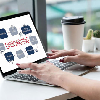 Manos teclean en un portátil con una pantalla de onboarding, junto a un café para llevar